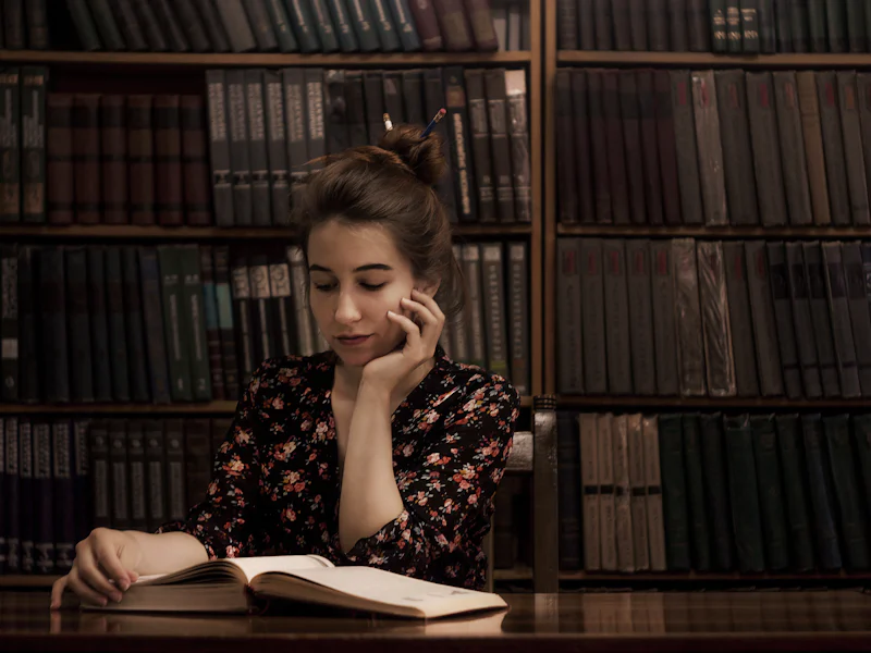Joven estudia concentrada con un libro abierto en una biblioteca